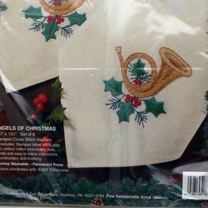 Puede incluir: Un juego de ocho servilletas de punto de cruz de 33 cm x 33 cm con un cuerno franc&eacute;s dorado con acebo y bayas rojas. El kit incluye tela estampada, hilo de bordar, una aguja e instrucciones. Lavable a m&aacute;quina y planchado permanente. Las servilletas combinan con el camino de mesa 83321.