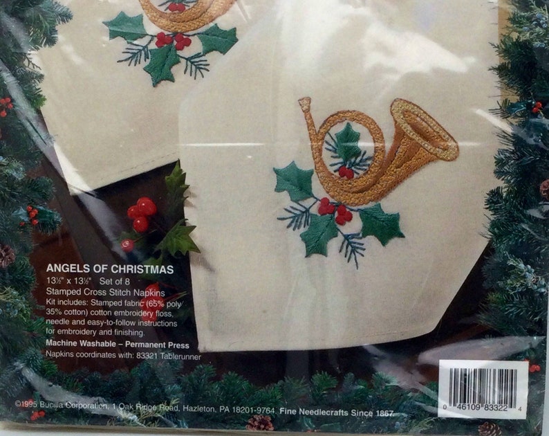 Puede incluir: Un juego de ocho servilletas de punto de cruz de 33 cm x 33 cm con un cuerno franc&eacute;s dorado con acebo y bayas rojas. El kit incluye tela estampada, hilo de bordar, una aguja e instrucciones. Lavable a m&aacute;quina y planchado permanente. Las servilletas combinan con el camino de mesa 83321.