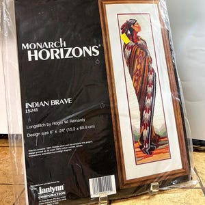 May include: A Monarch Horizons longstitch kit titled "Indian Brave" featuring a framed cross-stitch design of a Native American figure. The design measures 6" x 24" (15.2 x 60.9 cm). The kit includes Persian wool yarn, canvas, needle, instructions, and a stitch-by-number diagram.