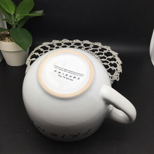 Puede incluir: Taza de cer&aacute;mica blanca con un logotipo de Friends negro y el texto "Friends The TV Series" en la parte inferior.