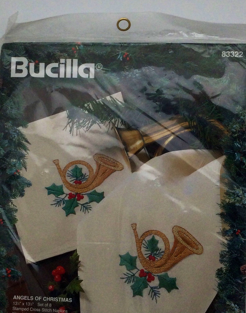 Puede incluir: Un juego de ocho servilletas de punto de cruz estampadas con un cuerno franc&eacute;s dorado con acebo y bayas rojas. Las servilletas est&aacute;n empaquetadas en una bolsa de pl&aacute;stico transparente con un anillo dorado en la parte superior. El paquete tambi&eacute;n incluye el texto "Bucilla&reg;" y "Angels of Christmas".