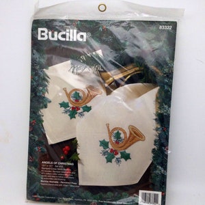 Puede incluir: Un kit de punto de cruz Bucilla "&Aacute;ngeles de Navidad" para 8 servilletas. El kit incluye tela estampada, hilo de bordar, una aguja e instrucciones. Las servilletas presentan un cuerno franc&eacute;s dorado con acebo y bayas.