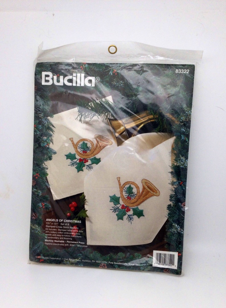 Puede incluir: Un kit de punto de cruz Bucilla "&Aacute;ngeles de Navidad" para 8 servilletas. El kit incluye tela estampada, hilo de bordar, una aguja e instrucciones. Las servilletas presentan un cuerno franc&eacute;s dorado con acebo y bayas.