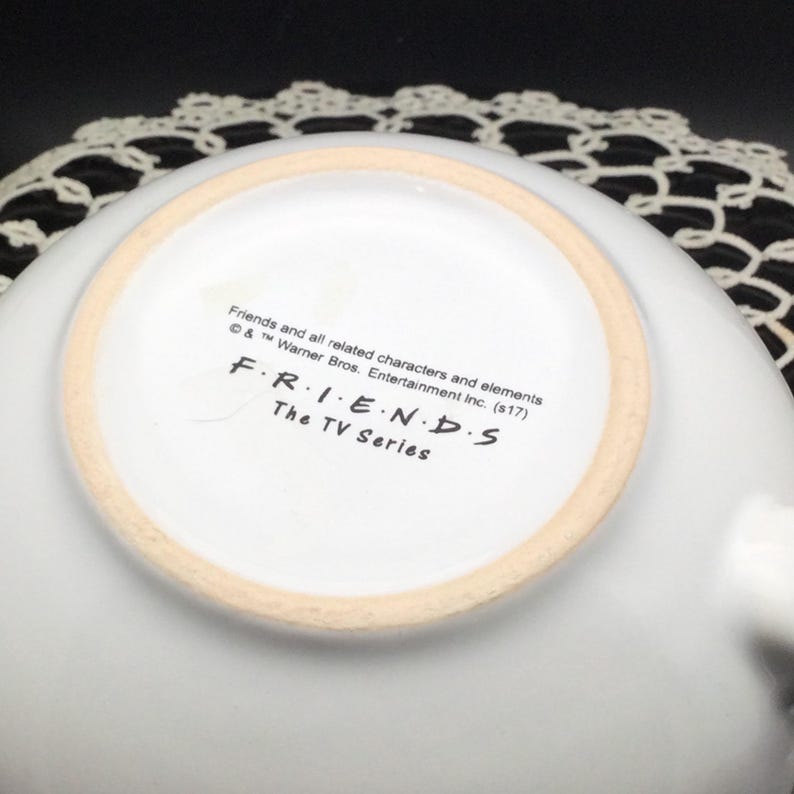 Puede incluir: Taza de cer&aacute;mica blanca con el logotipo de Friends y el texto "Friends and all related characters and elements &copy; & &trade; Warner Bros. Entertainment Inc. (s17) FRIENDS The TV Series" en la parte inferior.