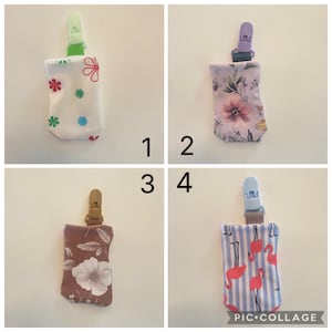 May include: Four fabric pacifier clips with different patterns. The patterns include flowers, floral, and flamingo designs. Each clip has a plastic clip at the top.