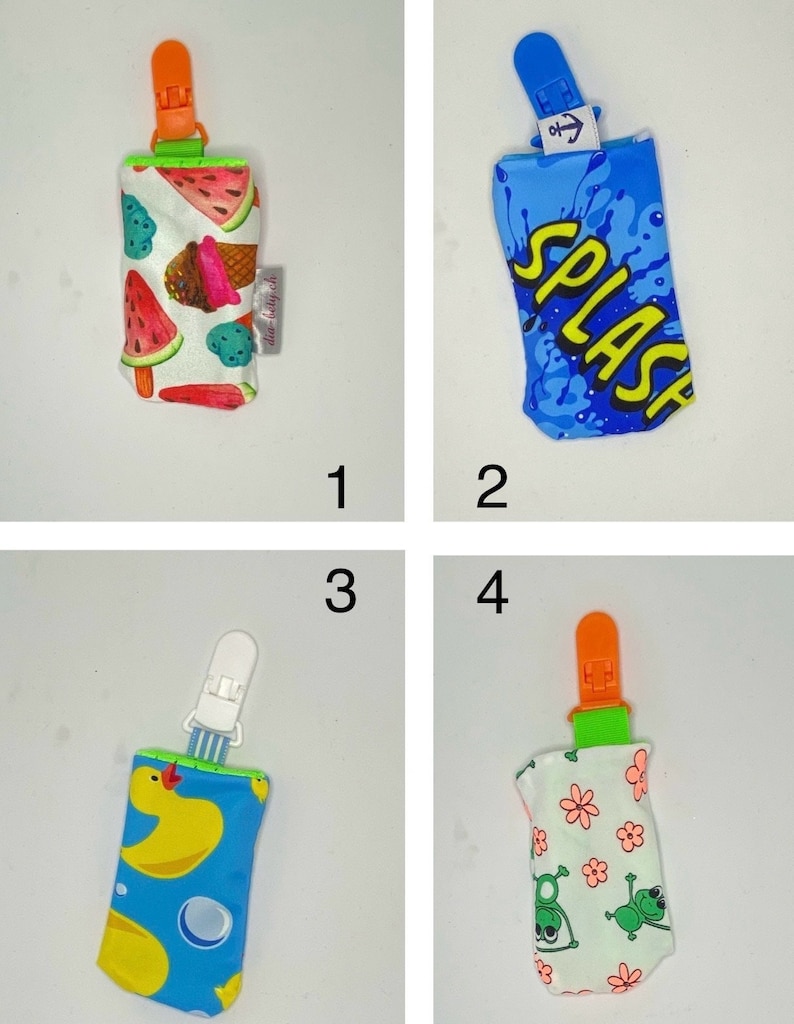 May include: Four pacifier clips with different fabric designs. One clip has a watermelon and ice cream pattern, another has a blue splash design with the word "SPLASH", a third has a yellow duck pattern, and the last has a frog and flower pattern.