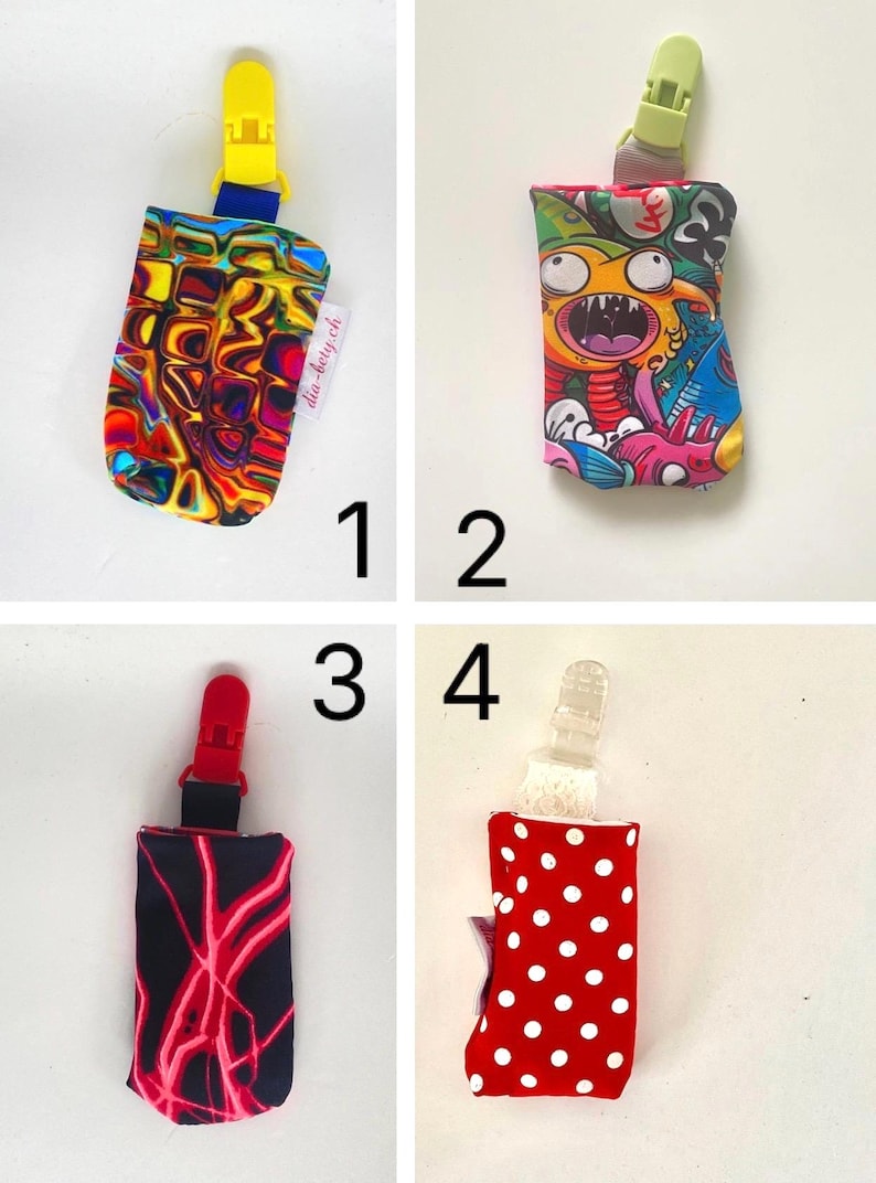 May include: Four baby bottle holders with clips. Designs include a colorful abstract pattern, a cartoon monster, a black pattern with red lightning, and a red polka dot pattern. Each holder has a different colored clip.