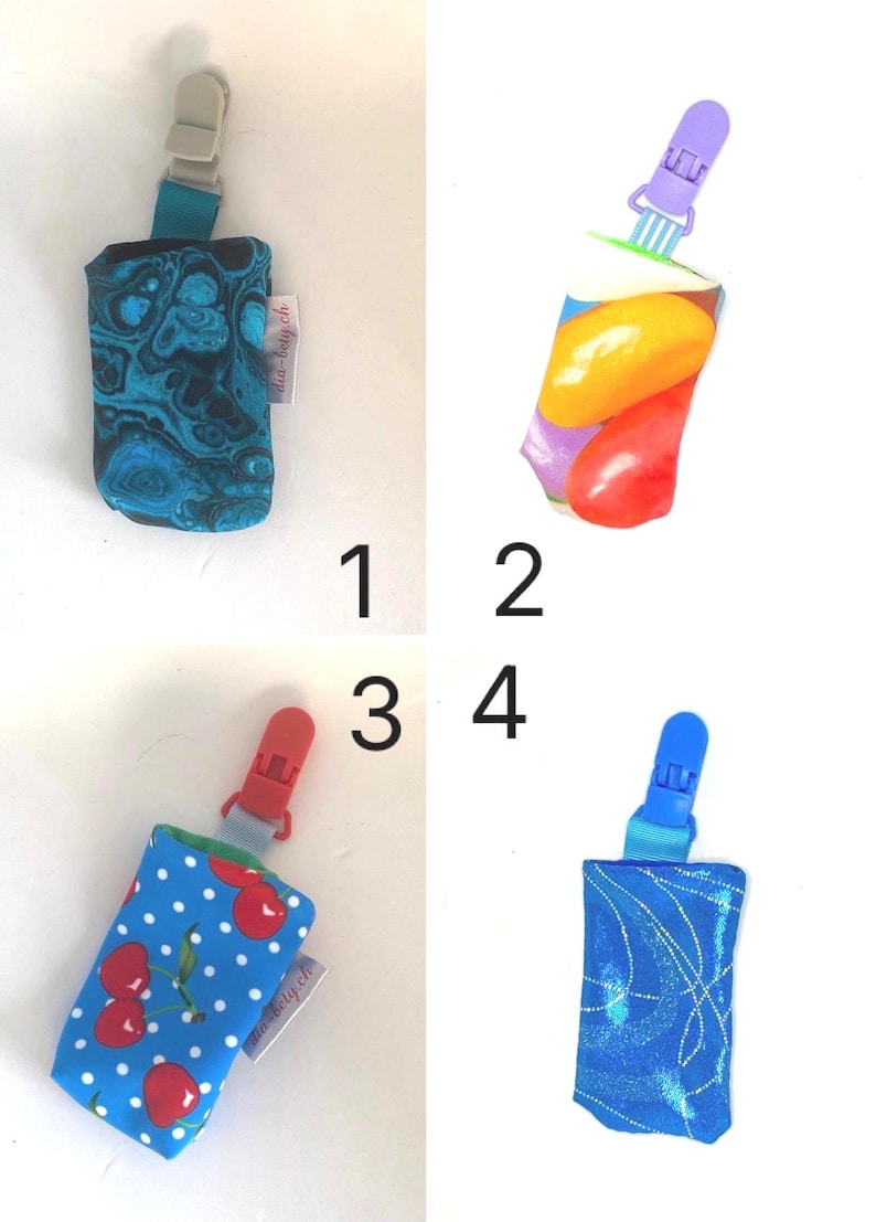 May include: Four pacifier clips with fabric pouches. The pouches feature various patterns: a blue and black swirl, a colorful fruit design, a blue cherry print, and a blue glitter pattern. Each clip has a different colored plastic clip.