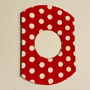 May include: Red fabric with white polka dots and a large white circle cut out in the center. The fabric is textured and has a slightly rough surface.