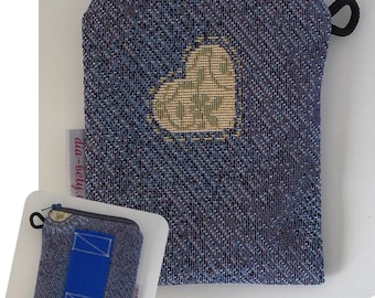 May include: A blue and purple woven zippered pouch with a heart design. The pouch measures 12 x 9 cm. The heart is beige and green. A smaller version of the pouch is also shown. The pouch has a black loop and a blue zipper.