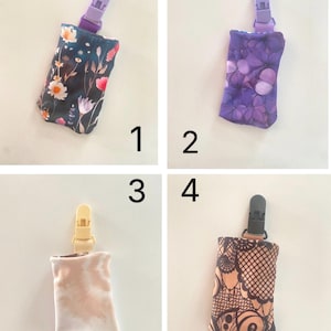 May include: Four fabric pacifier clips with different patterns. The clips have a plastic clasp at the top and a fabric pouch at the bottom. The patterns include floral, purple butterfly, tie-dye, and henna-style designs. The clips are numbered 1 through 4.