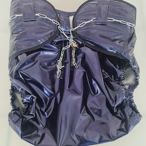 May include: A dark blue waterproof nappy cover with a chain and clips. The cover has a shiny, iridescent finish.