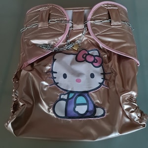 May include: A gold-coloured nappy cover with a pink Hello Kitty design and a chain with a lock around the waist.