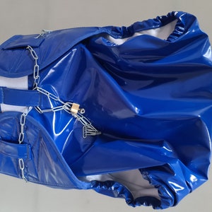 Peut inclure: Une couche en vinyle bleu avec une chaîne et un cadenas attachés. La couche a une ceinture élastique blanche et une doublure blanche.