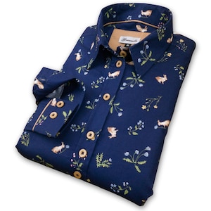May include: A navy blue long-sleeved shirt with a button-down collar and a pattern of small brown rabbits and flowers. The shirt has brown buttons and a tan label with the text "Treemantle" on the collar.