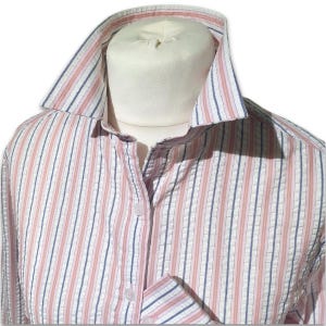 May include: A striped shirt in red, white, and blue, with a classic collar and a pocket. The shirt's fabric has a textured seersucker weave. The stripes run vertically down the shirt.