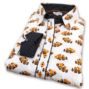 May include: White long-sleeve button-down shirt with a pattern of orange and brown clownfish. The shirt has a black and white polka dot collar and cuffs.