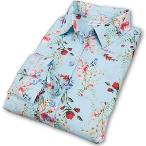 May include: A light blue long-sleeved shirt with a floral print featuring red, pink, and blue flowers on a light blue background.