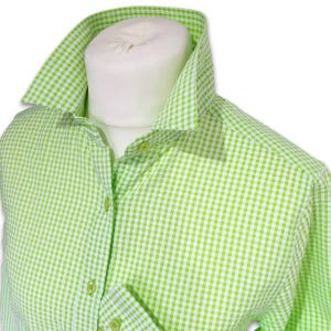 May include: A lime green and white checked shirt, displayed on a white mannequin. The shirt features a classic gingham pattern, with the collar and cuffs visible. The shirt is buttoned up, showing the details of the fabric.