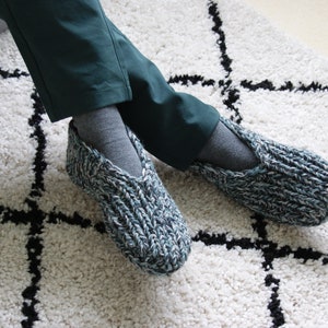 Puede incluir: Un par de zapatillas de punto azul y blanco con una abertura en forma de V en la parte superior. Las zapatillas se llevan puestas en los pies.