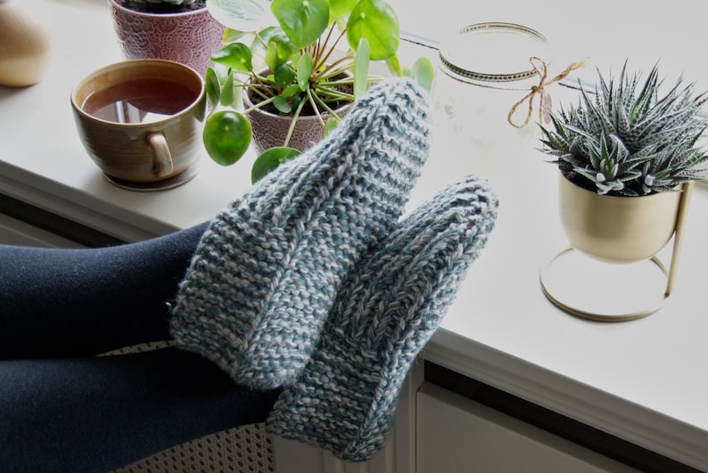 Puede incluir: Un par de zapatillas de estar por casa acogedoras, de punto, en color azul y blanco. Las zapatillas est&aacute;n hechas con un hilo grueso y tienen un dise&ntilde;o sencillo y cl&aacute;sico.