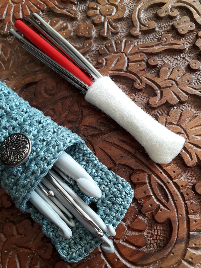 May include: A blue crocheted case with a silver button holds a set of crochet hooks. A white felt case holds a set of knitting needles.