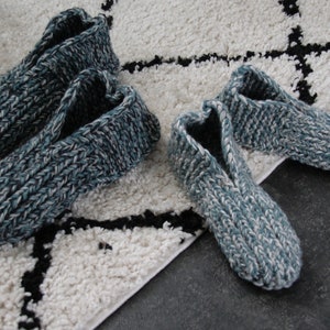 Puede incluir: Dos pares de zapatillas de punto en un esquema de color azul y blanco. Las zapatillas est&aacute;n sobre una alfombra blanca y negra.