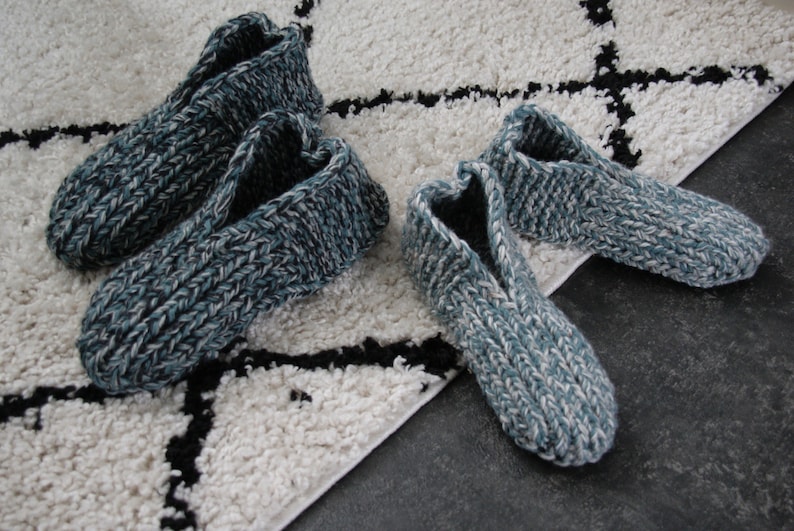 Puede incluir: Dos pares de zapatillas de punto en un esquema de color azul y blanco. Las zapatillas est&aacute;n sobre una alfombra blanca y negra.