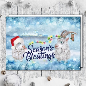 Könnte beinhalten: Eine Weihnachtskarte mit zwei weißen, flauschigen Tieren, einem Schaf und einer Ziege, mit einer Lichterkette und dem Text "Season's Bleatings".