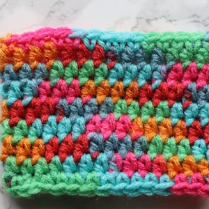 May include: A colorful crocheted fabric swatch with a variety of colors including pink, orange, green, blue, and red.