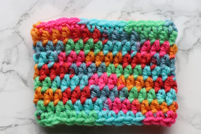 May include: A colorful crocheted fabric swatch with a variety of colors including pink, orange, green, blue, and red.