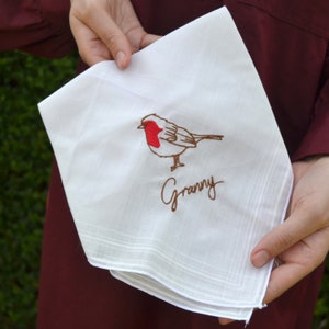 May include: White cotton handkerchief with an embroidered red-breasted robin and the word "Granny" in brown thread.