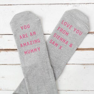 May include: Two gray socks with pink text. One sock says 'You are an amazing mummy' and the other sock says 'Love you from Sienna & Sam X'.