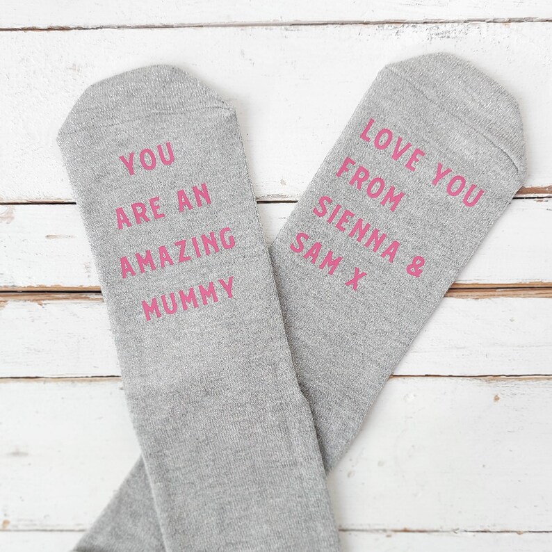 May include: Two gray socks with pink text. One sock says 'You are an amazing mummy' and the other sock says 'Love you from Sienna & Sam X'.