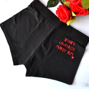 Könnte beinhalten: Schwarze Boxershorts mit rotem Text, der "Sophie's Favourite Mardy Bum" mit einem kleinen roten Herzen sagt.