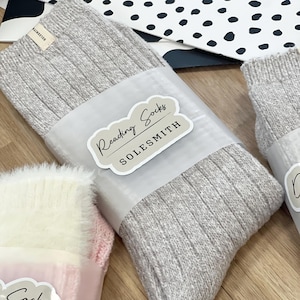 Può includere: Un paio di calzini da lettura in maglia a coste grigie con un'etichetta bianca che dice "Reading Socks SOLESMITH".
