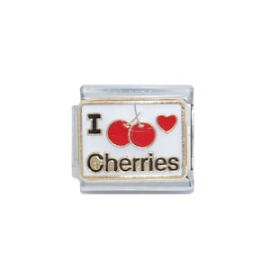 Puede incluir: Un charm para pulsera de plata con fondo blanco y borde dorado. El charm presenta un corazón rojo y dos cerezas rojas con tallos y hojas negras. El texto "I love Cherries" está escrito en letras negras.