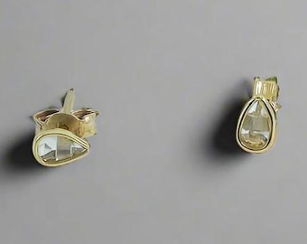 May include: A pair of gold teardrop-shaped earrings with clear crystal stones.
