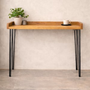 Handmade solid wood breakfast bar table with black hairpin legs, styled with a plant and coffee cup against a neutral wall.