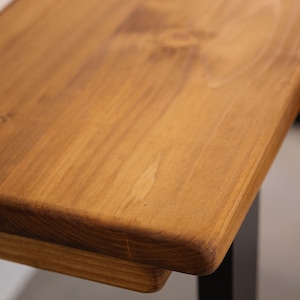 Close up of solid wood desk corner showing rounded edge detail and natural grain.