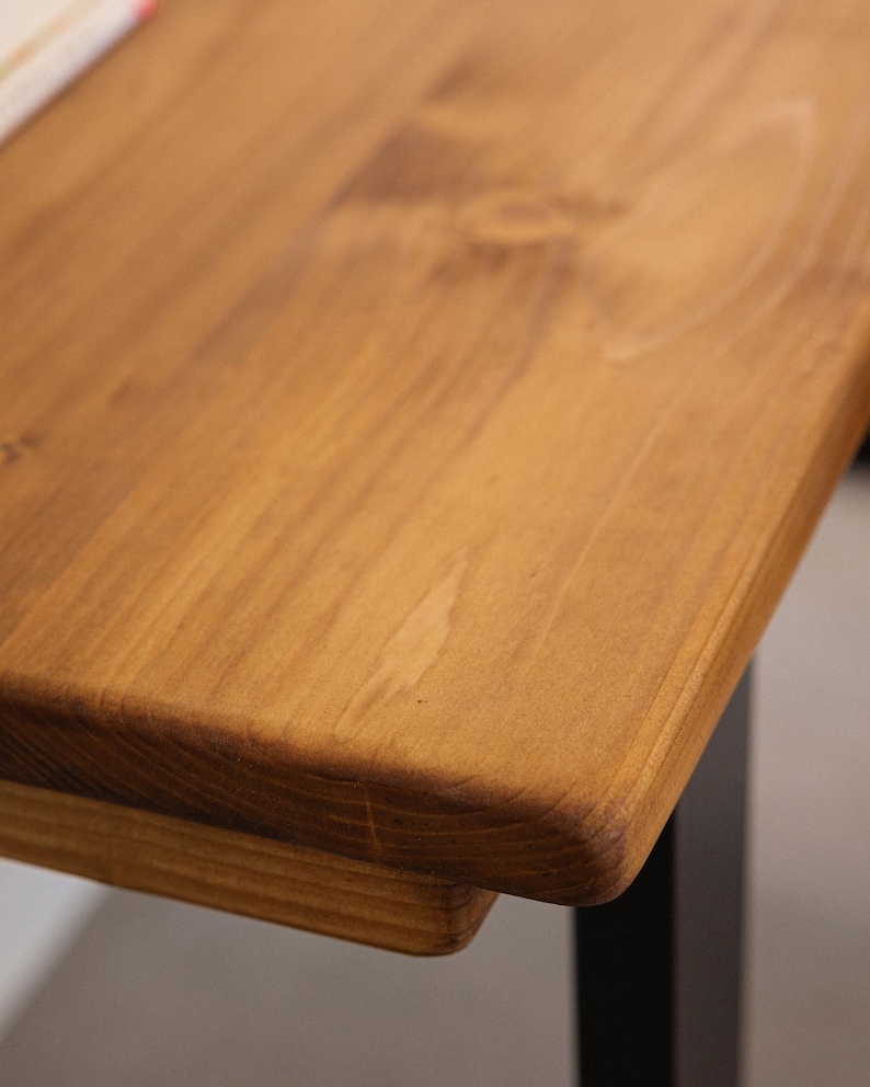 Close up of solid wood desk corner showing rounded edge detail and natural grain.