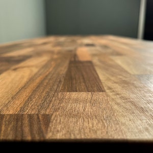 May include: A close-up of a wooden worktop with a light brown and dark brown wood grain pattern.