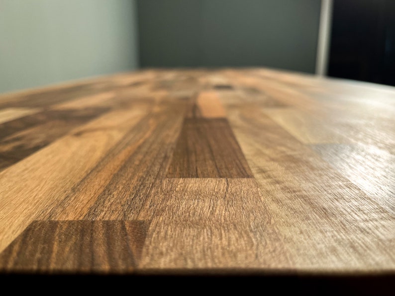 May include: A close-up of a wooden worktop with a light brown and dark brown wood grain pattern.