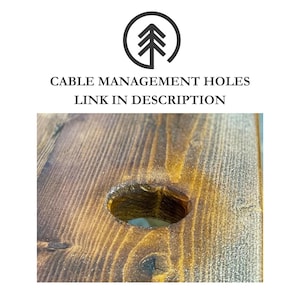 Close-up of a wood surface with a round hole drilled through it. The hole is approximately 6cm in diameter and has a rounded edge. The wood is a dark brown colour and has a natural grain pattern.