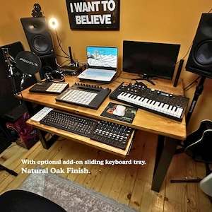 Solid wood desk in a music home studio, in a light colour finish and black steel legs. The desk features an optional add on sliding keyboard tray.