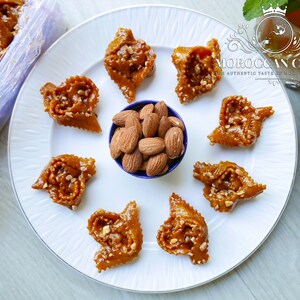Chebakia moroccan cookies encircling a bowl of almonds on a round white plate.
A hot cup of moroccan mint tea is ready to accompany this gourmet dessert.