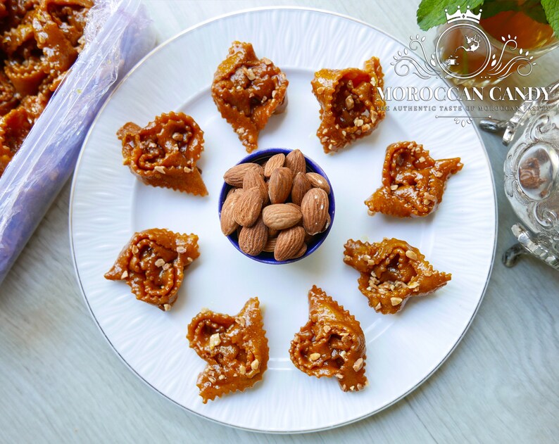 Chebakia moroccan cookies encircling a bowl of almonds on a round white plate.
A hot cup of moroccan mint tea is ready to accompany this gourmet dessert.