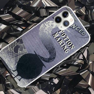 May include: A white iPhone case with a blue and white design. The design features a cauldron and the text "Potion Making" in a white font. The case has a camera lens cutout and a text overlay that reads "Advanced Borages".