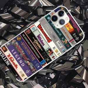 May include: A white ceramic mug with a black handle and the text "But First, Coffee" in a bold, black font. The mug is set against a blurred background. The mug appears to be approximately 10 cm tall.