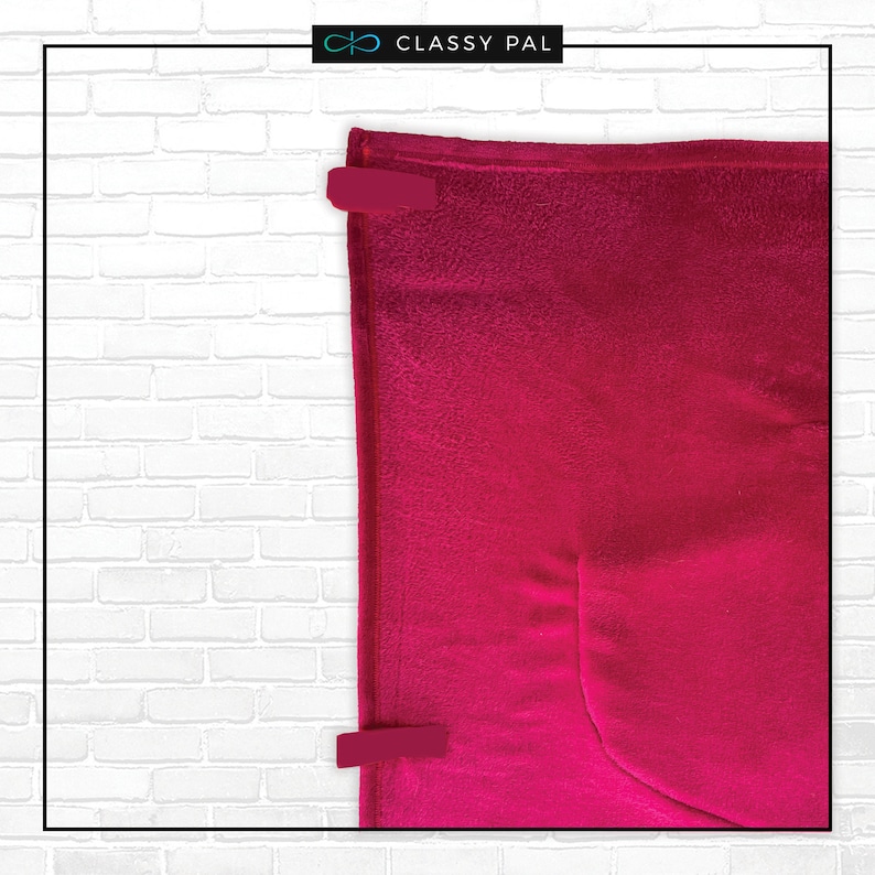 May include: A bright pink fleece blanket with a pocket on the bottom right corner. The blanket is folded and secured with two red clips.